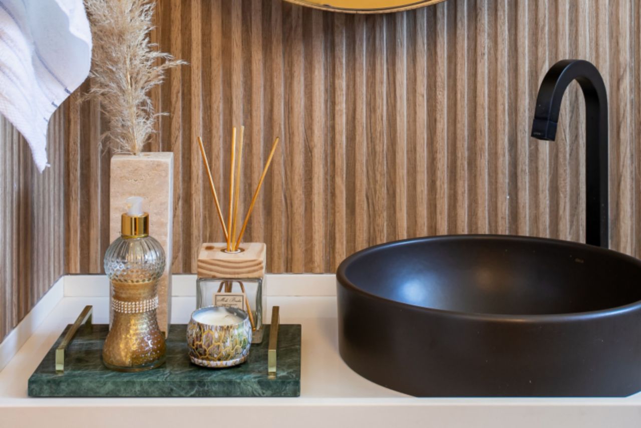 Bathroom sink with fluted, wood-look tile backsplash.