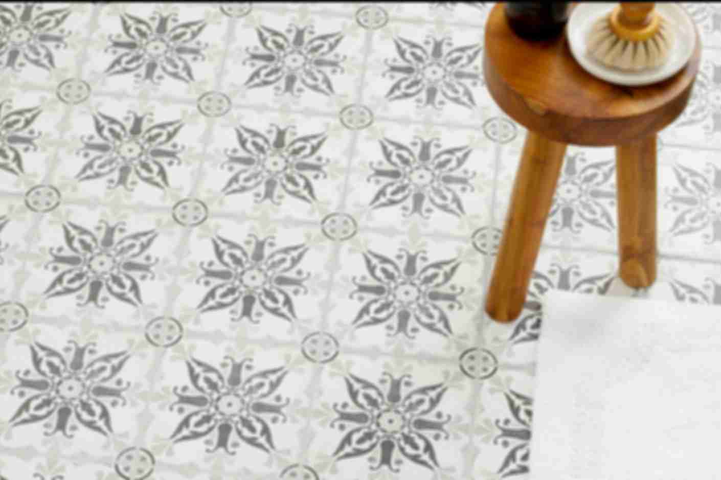 Tiled floor with a light and dark grey floral pattern and a wooden accent stool.