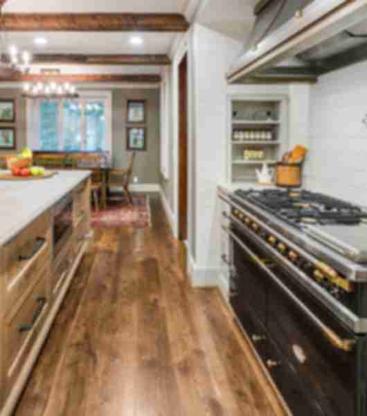 Galley kitchen with stove and counter tiled in wood-look luxury vinyl flooring.