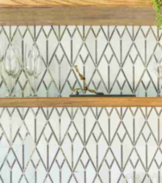 Bar area with an a backsplash covered in mixed-stone art deco mosaic tile featuring diamonds, chevrons and triangles.