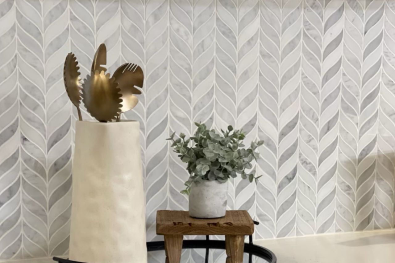 White and Grey chevron mosaic tile behind counter with jar of cooking spoons and small plant