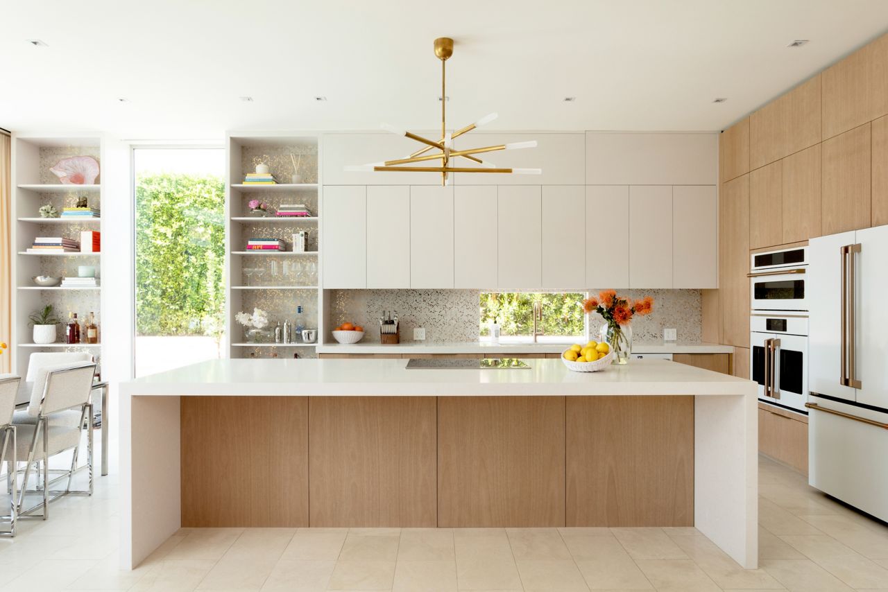 This glamorous kitchen features a white marble floor and a white with gold flecked tile backsplash. 