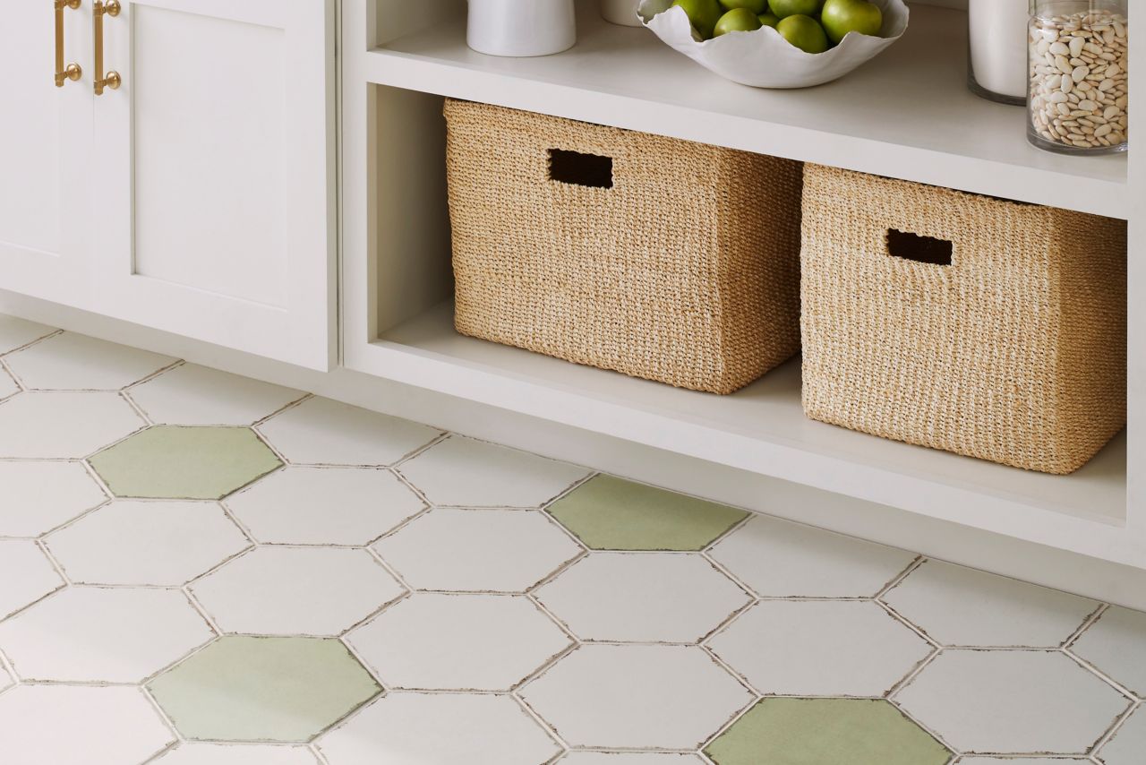 Kitchen area tiled in ceramic tile on floors and walls floor tile is a hexagon in mostly white with sage green scattered throughout while tile is 6 by 6 square tiles in a plain white and one with a lace pattern I'll have natural edges. 