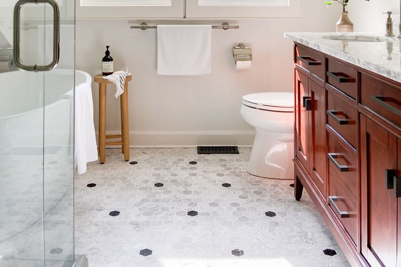 Bathroom with hexagon tile floor in a white with black polka-dot pattern.