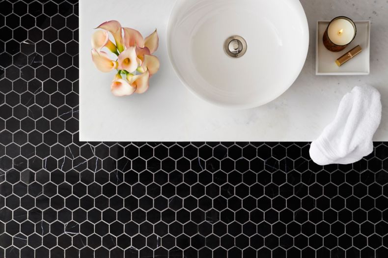 Sophisticated bathroom with black marble hexagon mosaic on floor.