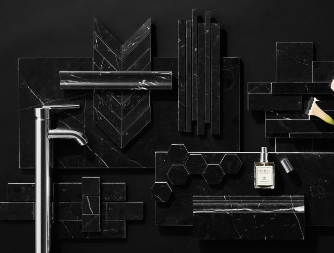 Black Marquina marble tile in various shapes and sizes with chrome faucet,  calla lily, and perfume bottle.