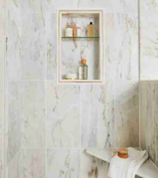 Beautiful polished marble shower with grey and gold veining, a shower niche and corner seat.