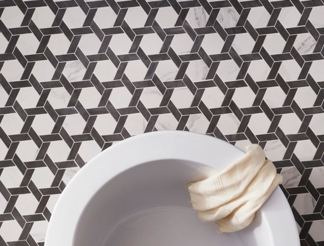 Black and white hexagon-shaped, marble-look floor tile in bathroom with freestanding tub.