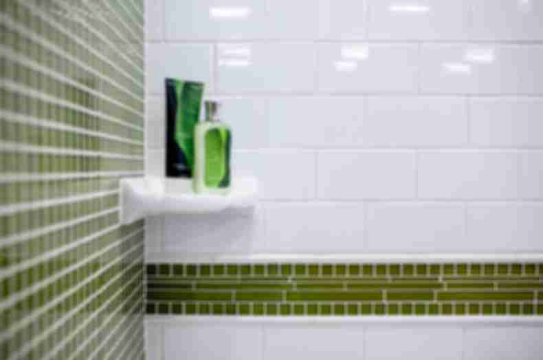 White subway wall tile and green glass mosaic tile on shower wall.