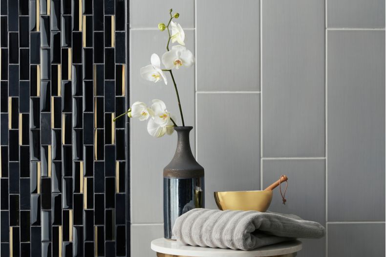 Contemporary shower wall with grey large-format tile and black and gold glass mosaic.