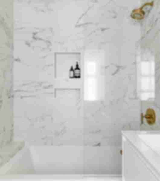 Shower with white marble-look tile with grey veining.
