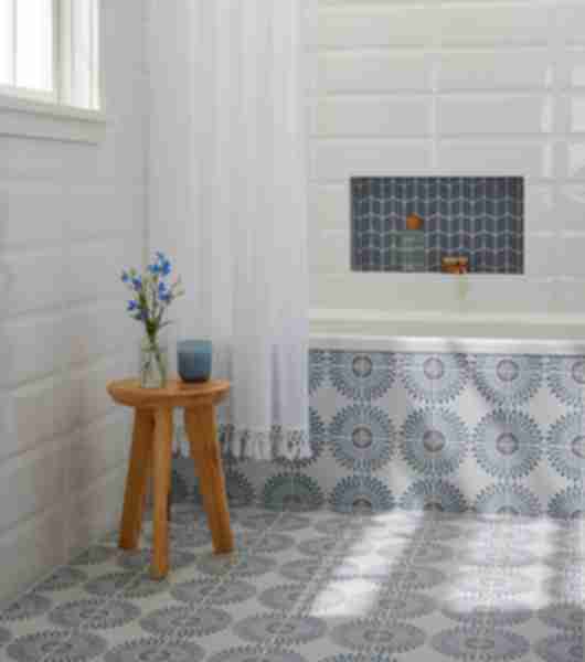 Bathroom featuring blue and white patterned tile on the floor and up the exterior side of the tub wall.