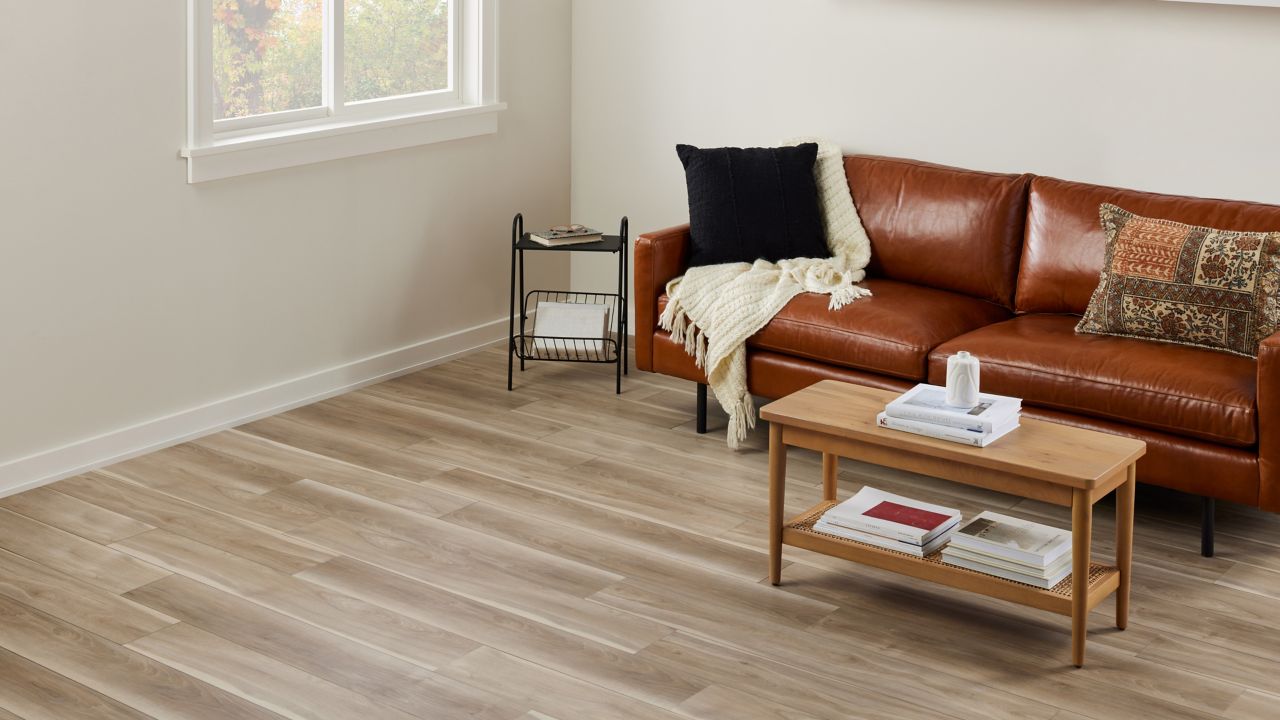 Living room with light brown luxury vinyl flooring and brown leather sofa.