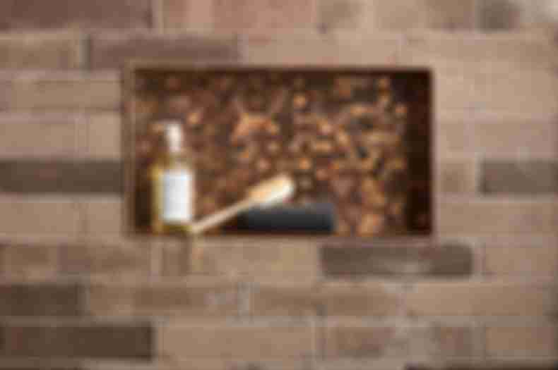 Brick subway wall tile in shower with copper penny round in recessed shelf.