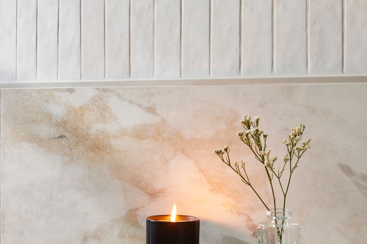 White wall and sink with a candle and small plant.