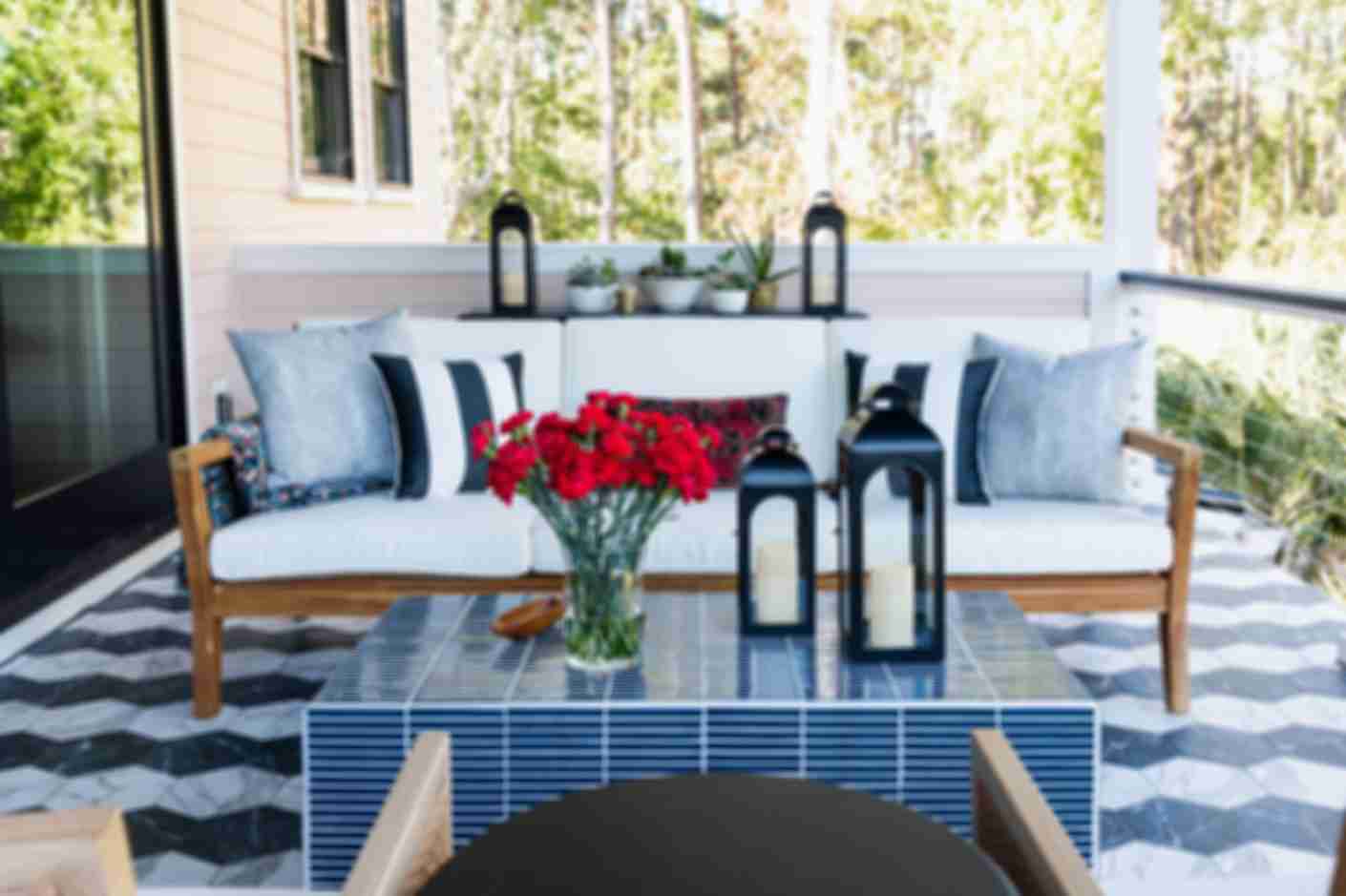 White outdoor sofa on a back porch with a custom tiled floor pattern made of black and white marble hex tiles.
