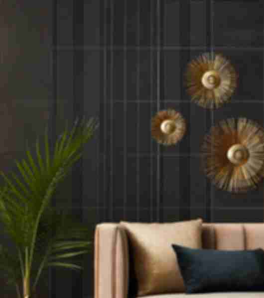 The wall behind a sofa is covered in black ceramic tile featuring three pattern variations of small gold metallic points. The overall effect of the tile is similar to tufted black fabric upholstery.