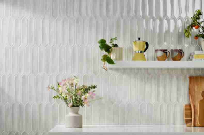 Kitchen backsplash tiled in white handmade picket tile with fresh flowers sitting on countertop and a white shelf holding kitchenware.