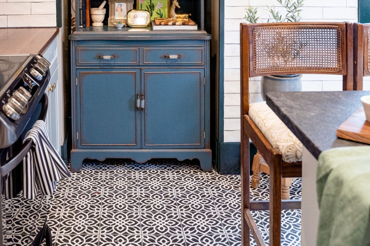 Kitchen with patterned tile floor, white tile wall and blue hutch.