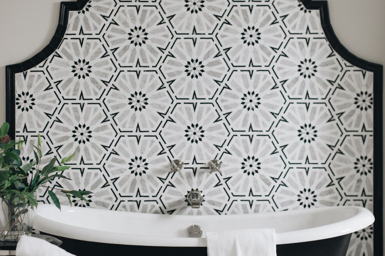 Black and white mosaic wall tile with tub and black and white checkerboard floor.