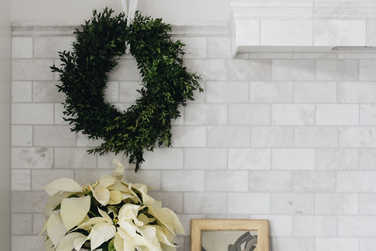 Kitchen with white marble subway tile backsplash and wreath.