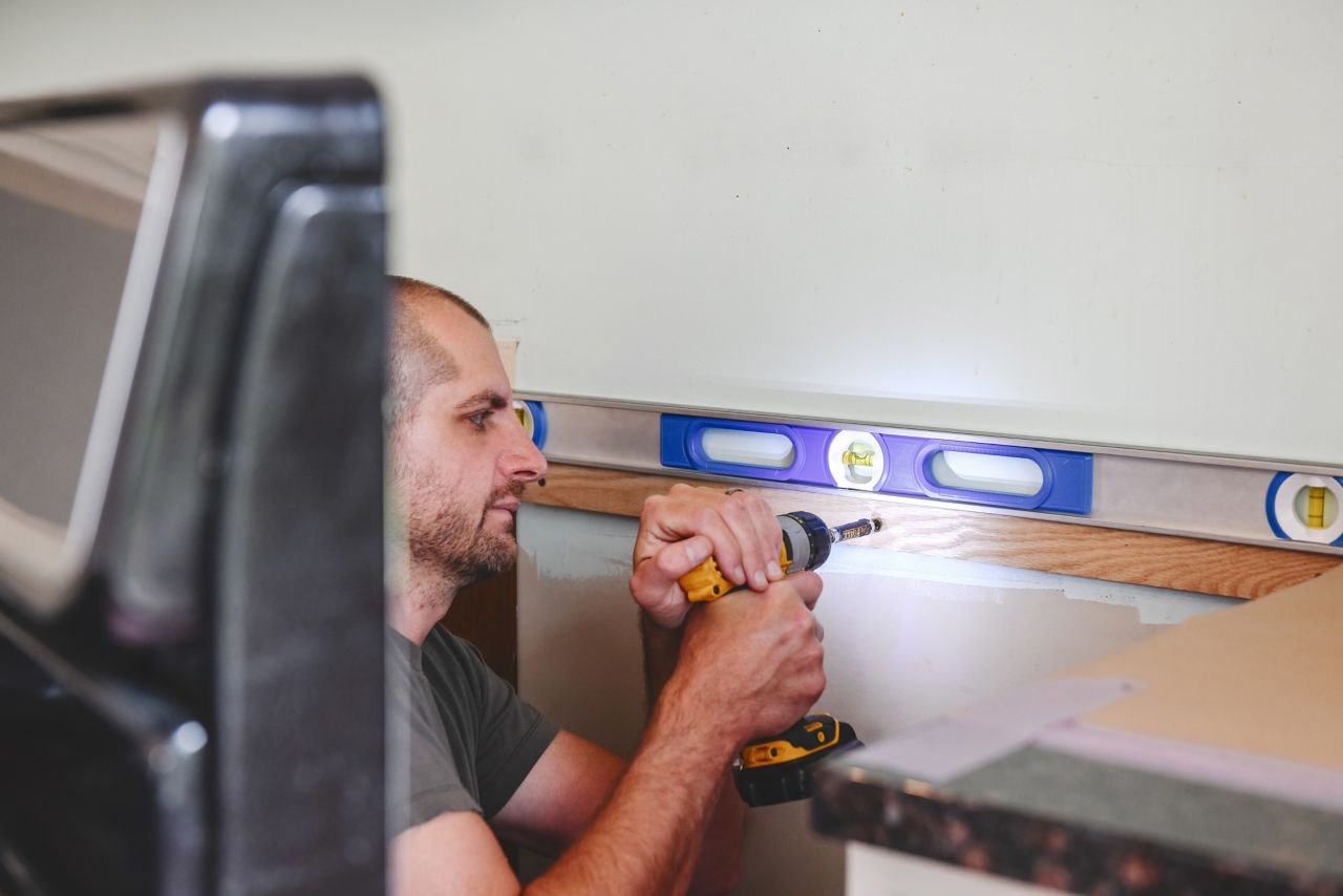 Installing ledger board to support the weight of a subway tile kitchen backsplash behind a stove.