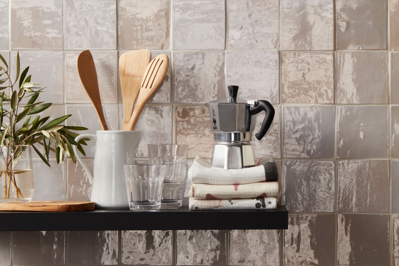 This kitchen wall is covered in glossy beige ceramic handmade Moroccan tile. Each of the square tiles has subtle variation in color and texture, which adds depth to an otherwise simple tiled surface.