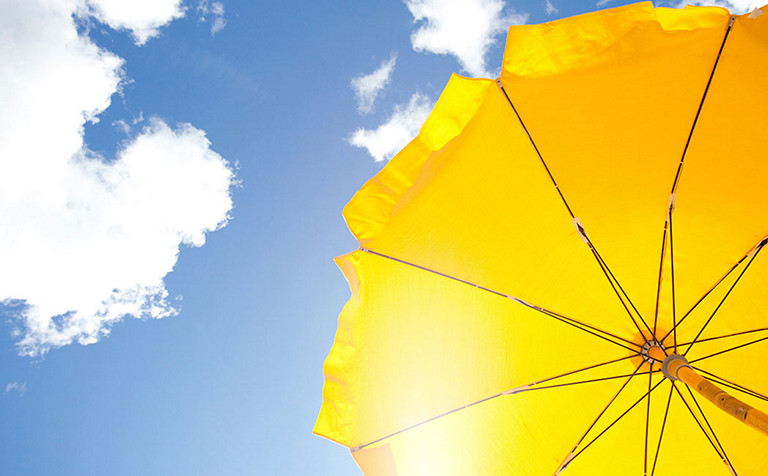 阳光下的黄色沙滩伞