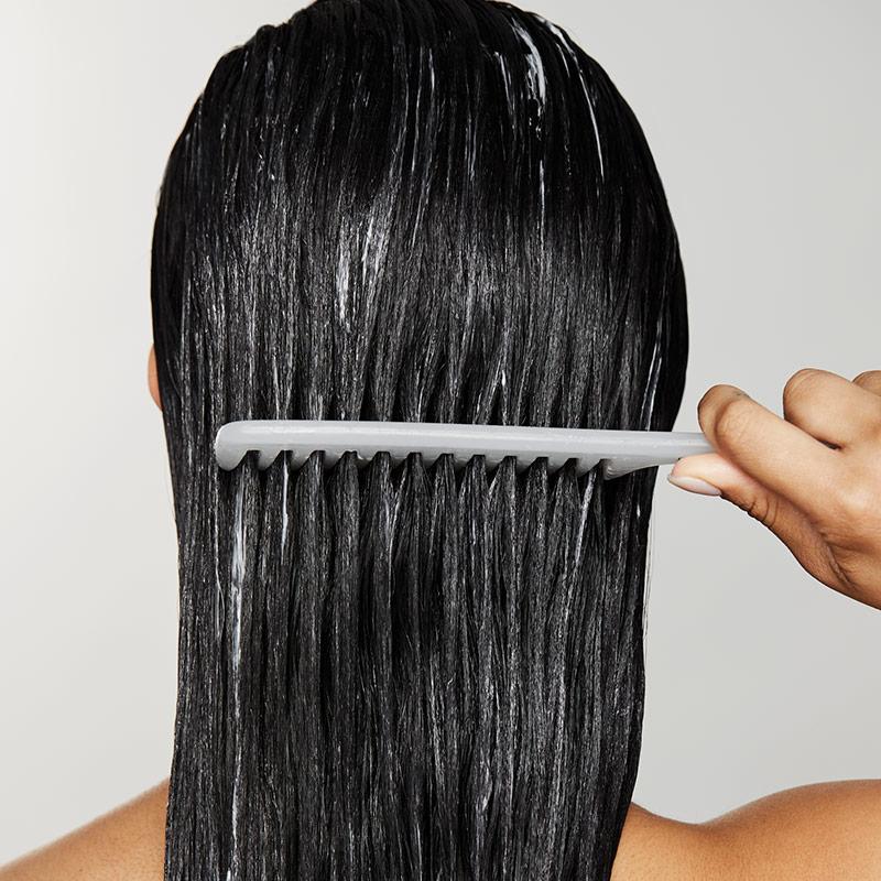 image of woman combing conditioner through her hair