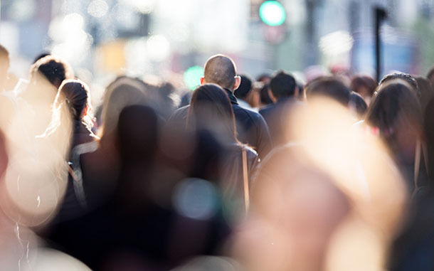 Heads of shoppers and commuters in a busy urban street scene.