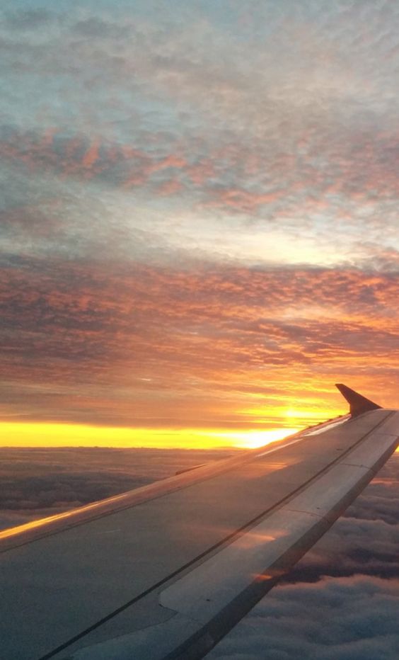 A view of an airplane wing against a cloudy sunset sky.