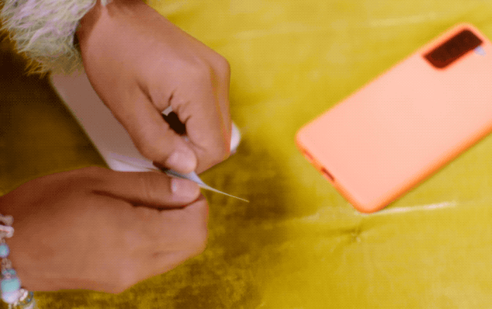 A person peels a picture off its sticky back and sticks it on a phone case