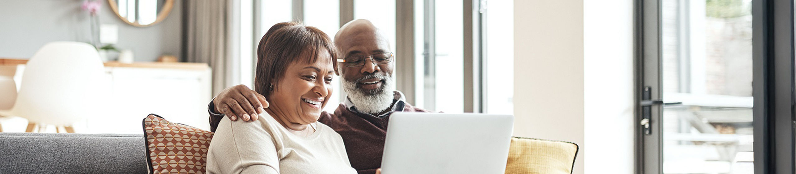 An elderly couple looks at a laptop screen