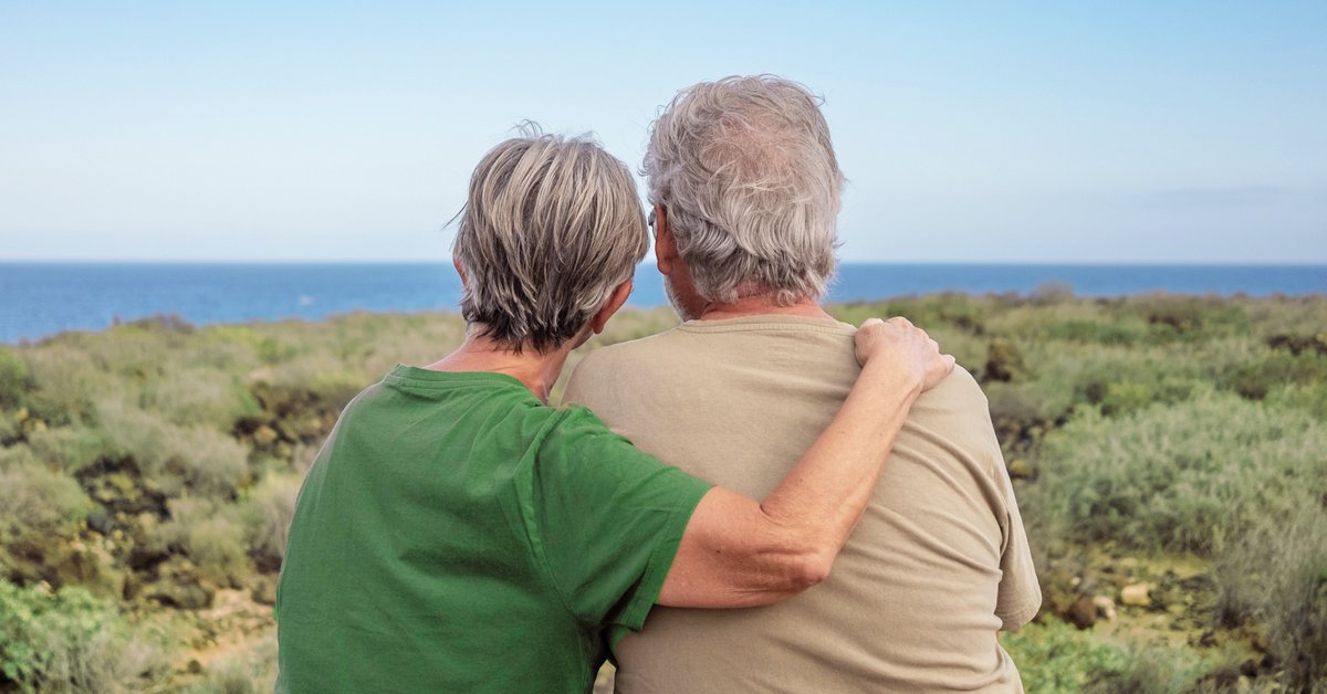 a man and woman looking out over a cliff onto the ocean