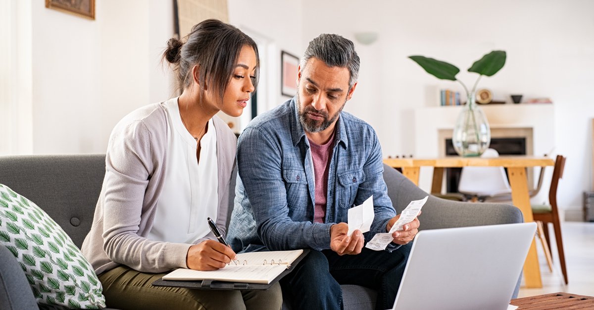 In a professional office setting, a businessman and businesswoman are engaging in a meeting, utilizing their laptops.