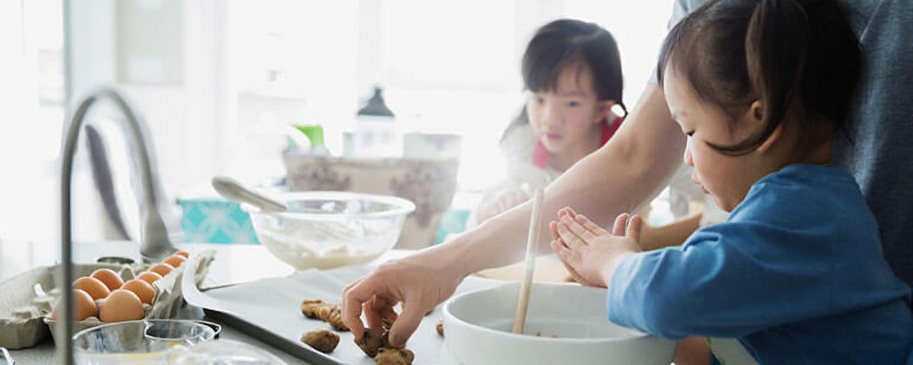 A father and his young daughters washing their hands while baking in their kitchen