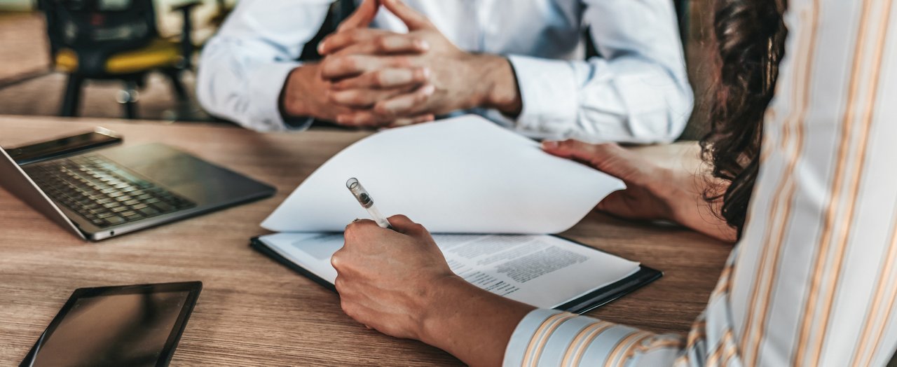 Un homme d'affaires dans un cadre de bureau est vu en train de signer un contrat, entouré d'autres professionnels.