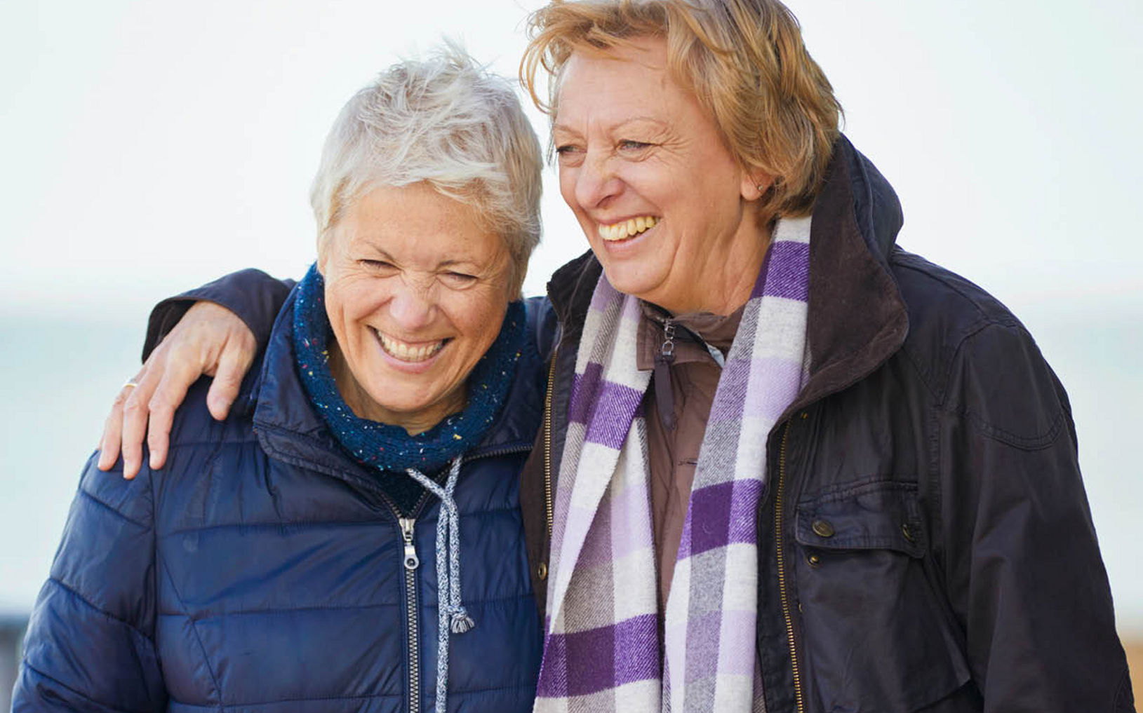 Two people in winter jackets standing together outdoors, one with an arm around the other.Provide your feedback on BizChat