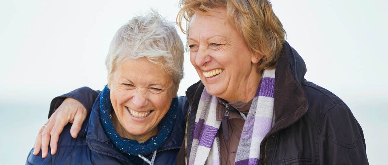 Two people in winter jackets standing together outdoors, one with an arm around the other.Provide your feedback on BizChat