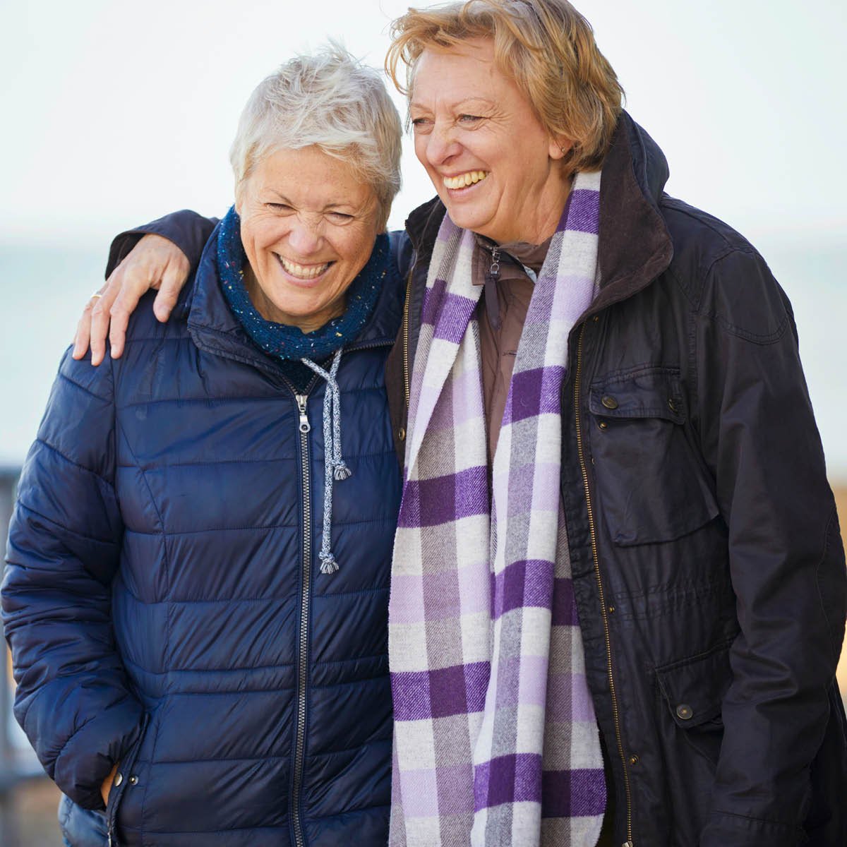 Two people in winter jackets standing together outdoors, one with an arm around the other.Provide your feedback on BizChat