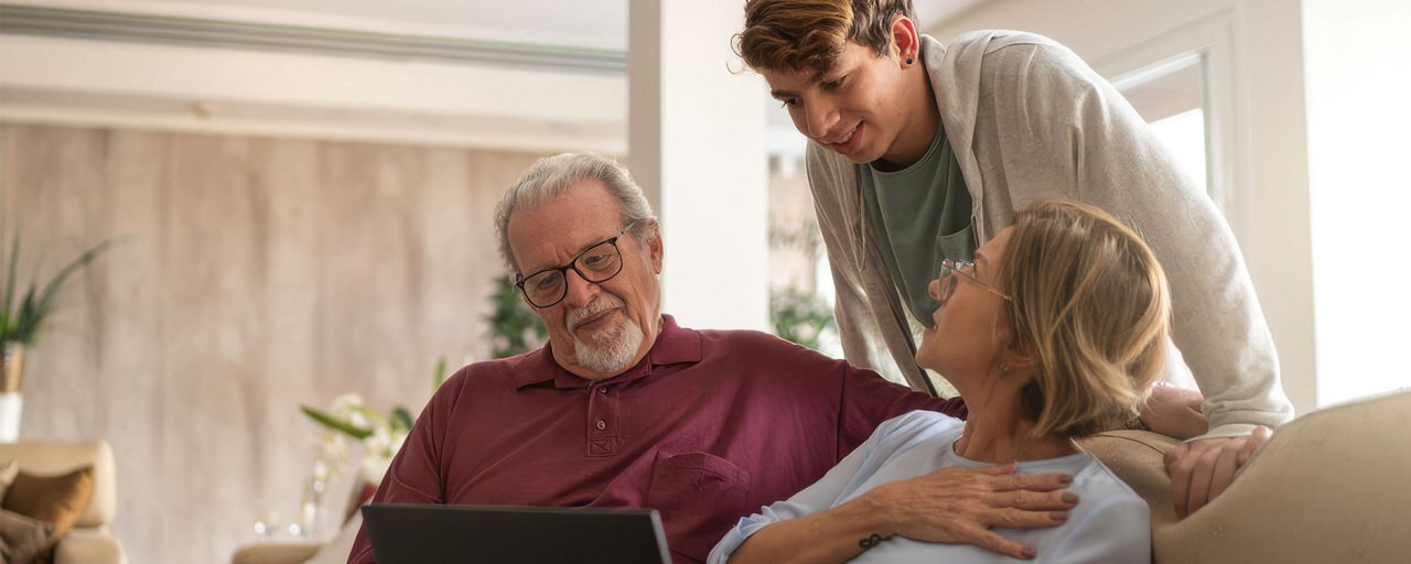 Grandparents looking at photos with their grandson on a sofa