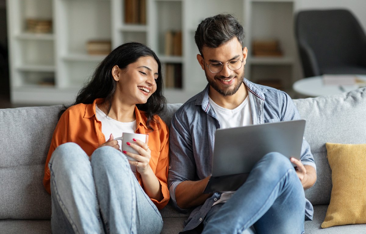 Couple sitting on couch looking at laptop