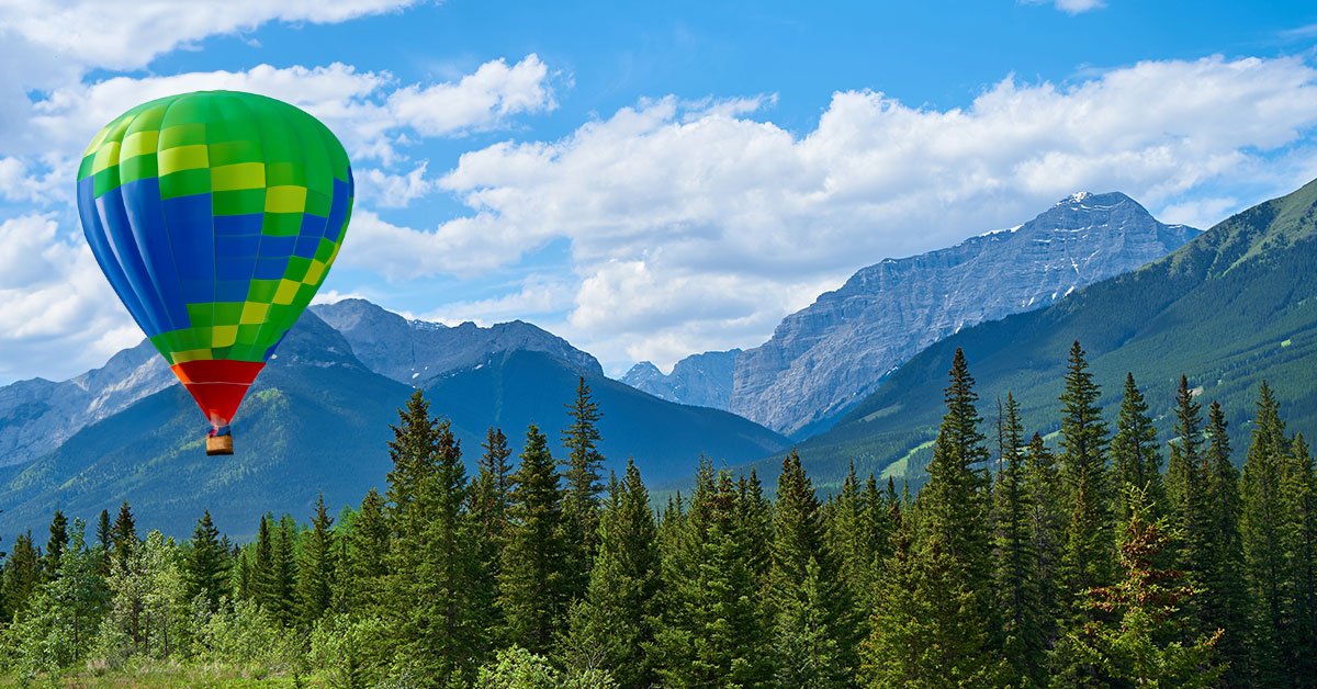 Profitez du paysage à couper le souffle des montagnes enneigées, au milieu d'une forêt verdoyante sous le ciel bleu clair.