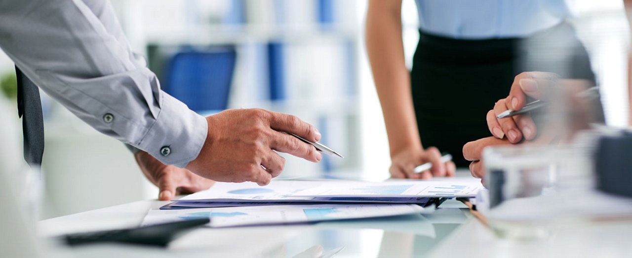 Un gros plan met en évidence les mains d'un homme d'affaires, soulignant l'atmosphère professionnelle du bureau.