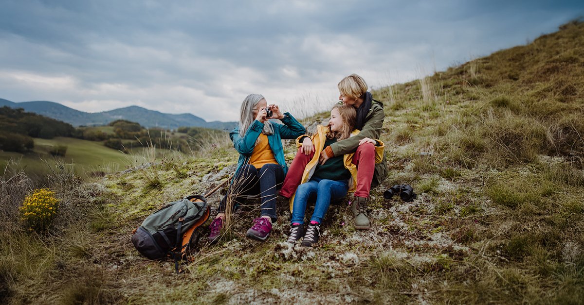 A couple enjoys a summer hiking adventure in nature, both adults carrying backpacks, exemplifying family travel.