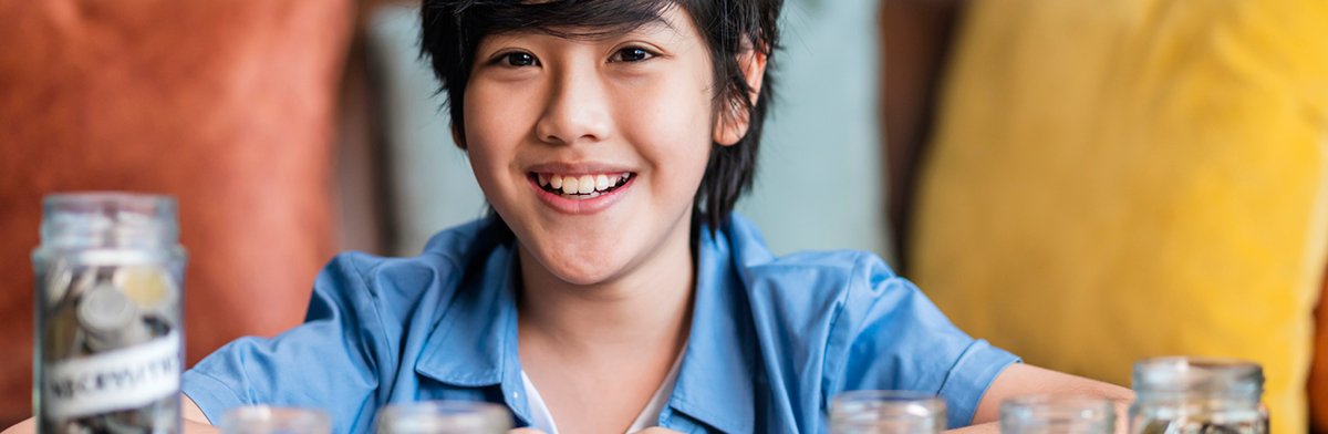 A cheerful boy beams as he holds a glass of water, showcasing his joyful expression.