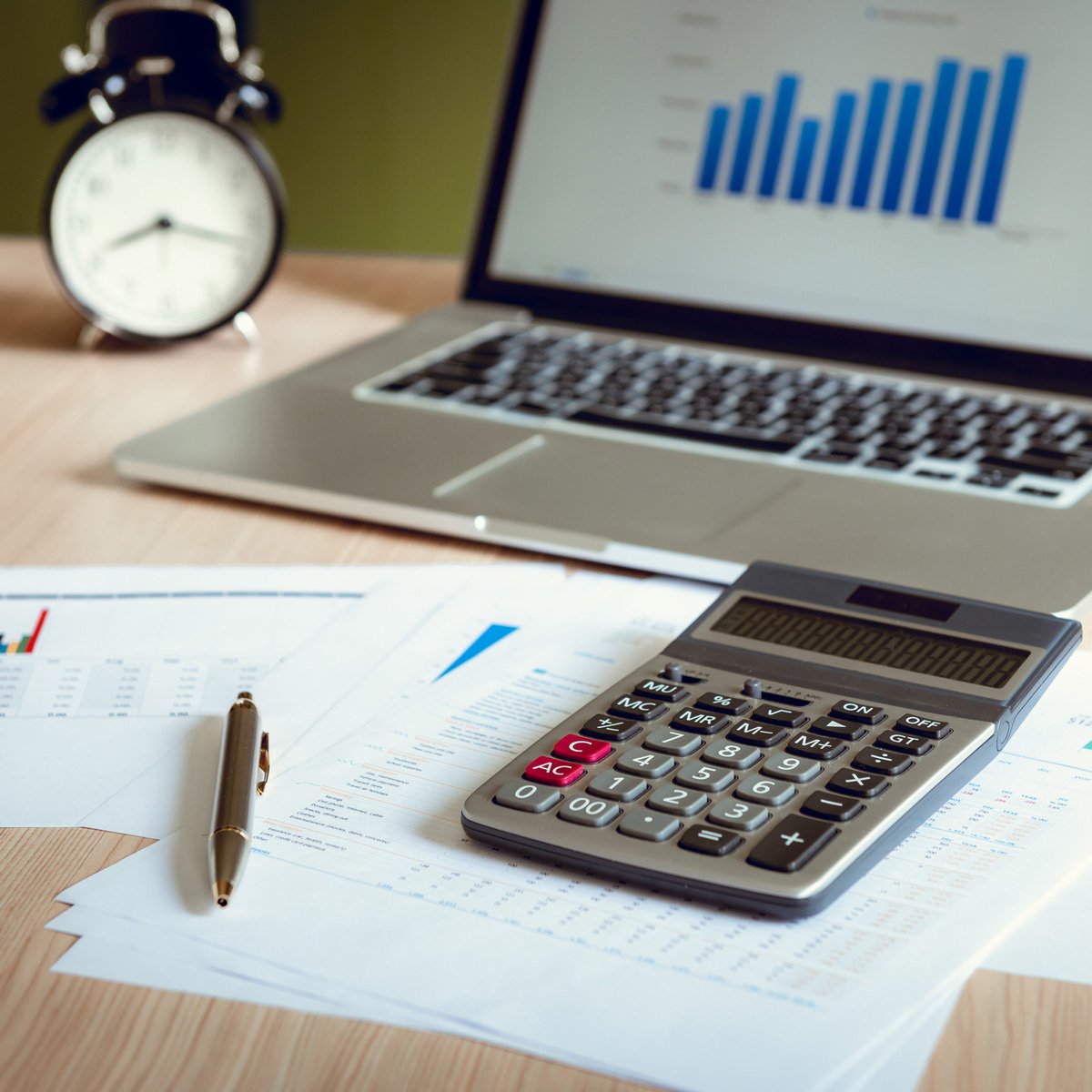 Un stylo, une calculatrice et un bloc-notes reposent à côté d'un ordinateur portable et d'un clavier, incarnant la technologie de bureau essentielle pour la finance d'entreprise.