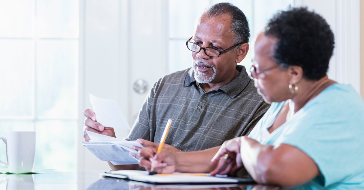 Un homme professionnel, probablement un médecin, discute d'affaires avec une femme dans un cadre de bureau, tous deux utilisant des ordinateurs portables.