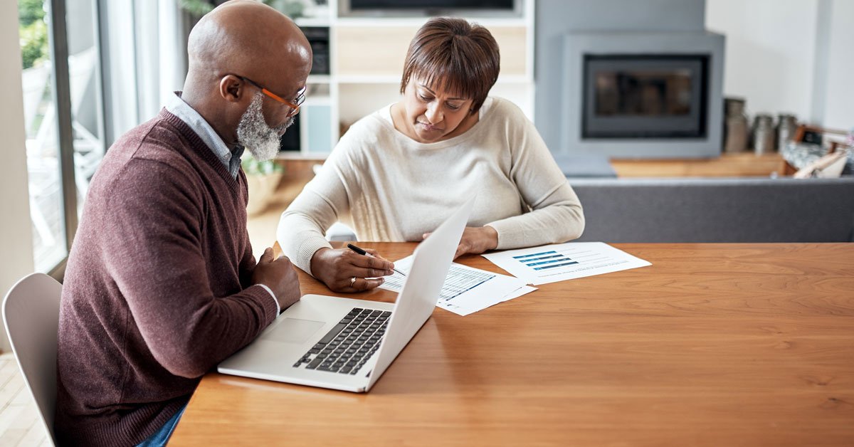A businessman and a businesswoman, engaging in a professional discussion with a laptop computer at hand.