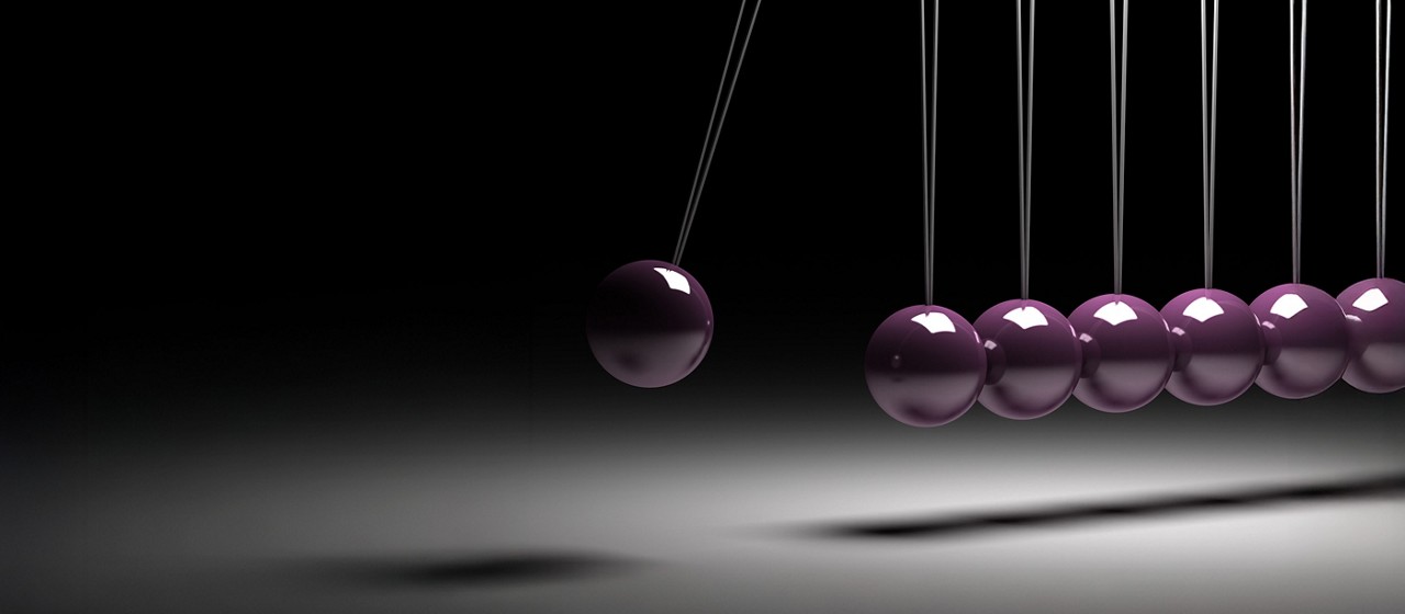 Un groupe de sphères chromées, conçues en 3D, représente une boule rouge en équilibre dans un berceau de Newton, symbolisant l'équilibre.